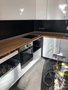 Cuisine en cours de rénovation avec pose des meubles blanc, plan de travail sur mesure, évier, équipements électriques et carrelage sol et mur par EDVA