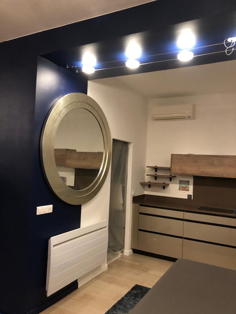 Cuisine rénovée avec mobilier sur mesure, miroir rond, éclairage intégré et climatisation - Réalisation EDVA dans les Alpes-Maritimes