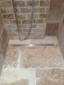 Détail douche en travertin avec caniveau – EDVA Rénovation