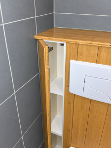 Rangement intégré à côté des toilettes dans une salle de bain rénovée